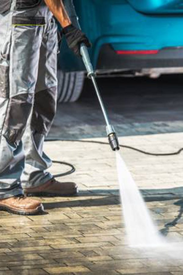 Cobble Driveway Pressure Washing by Caucasian Worker.